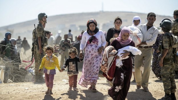 Сирийские курдские беженцы проходят мимо солдат, когда они пересекают границу из Сирии в Турцию, провинция Шанлыурфа, сентябрь 2014 г.