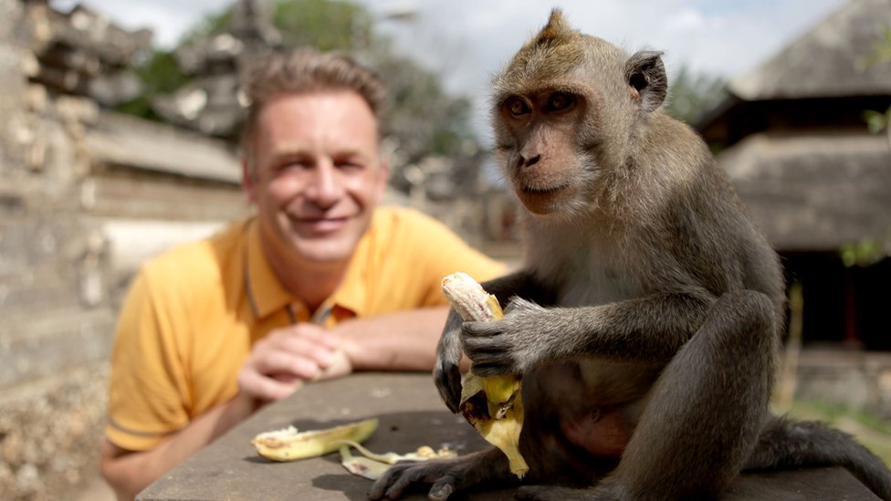 Chris Packham sonrie junto a un mono.
