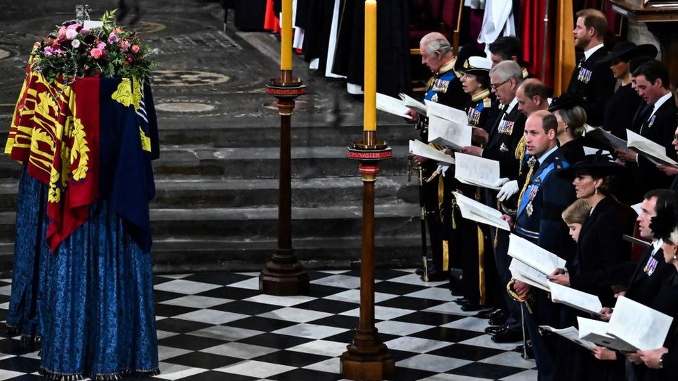 Miembros de la familia real e invitados cantan mientras el féretro de la reina Isabel II, cubierto con el estandarte real, yace junto al altar de la Abadía de Westminster