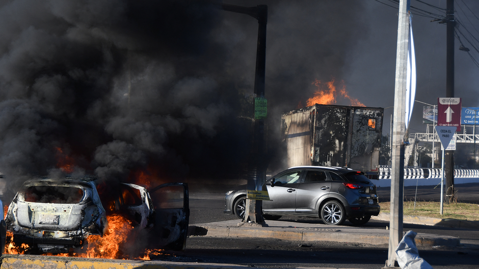 Burning vehicles are seen blocking a road following the arrest of Ovidio Guzmán-López.