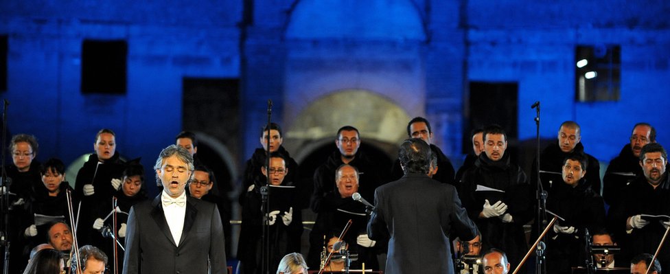 Итальянская оперная звезда Андреа Бочелли (слева) выступает на сцене с Симфоническим оркестром Абруццо в Колизее в Риме 25 мая 2009 г.