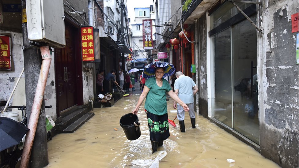 福建建甌，一名婦女行過被洪水淹沒的街道