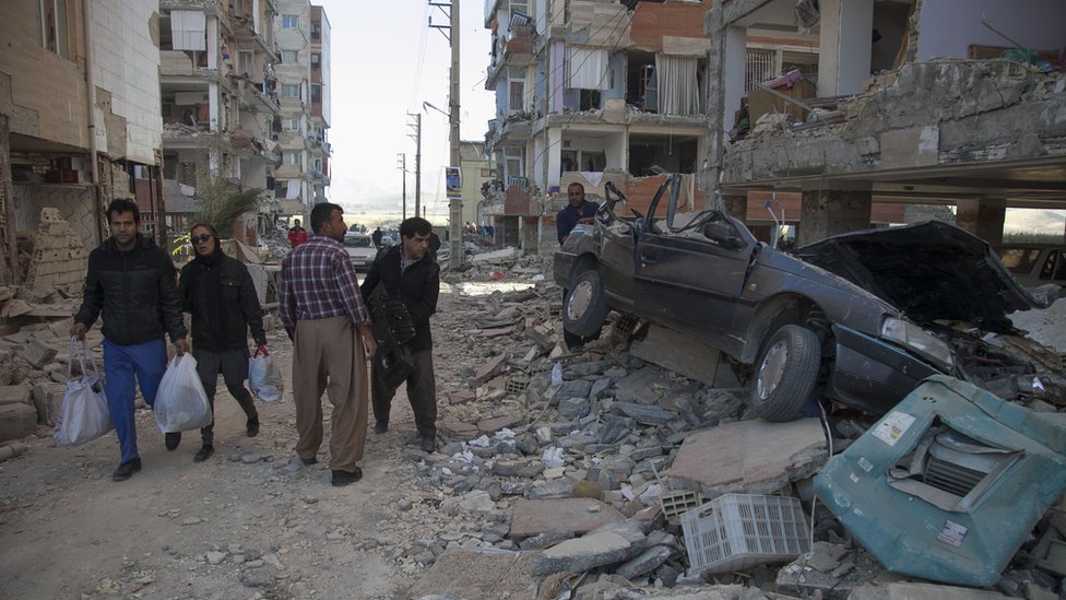 Transeúntes observan los destrozos y escombros dejados por el terremoto en Irán