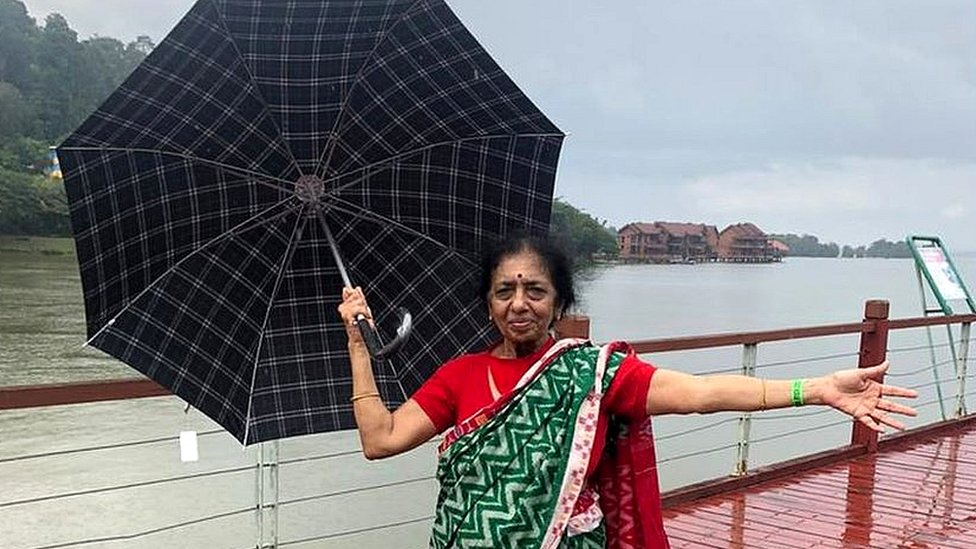 Nalini standing with an umbrella in front of a large body of water