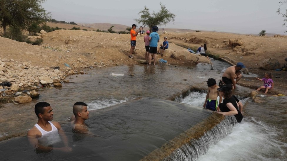 Палестинская молодежь и еврейские поселенцы собираются на водоеме недалеко от оккупированной деревни Аль-Ауджа на Западном берегу в долине реки Иордан 15 мая 2020 года, когда регион приближается к аномальной жаре