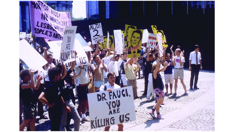 Активист по борьбе со СПИДом держит табличку с надписью: «Доктор Фаучи, вы нас убиваете»