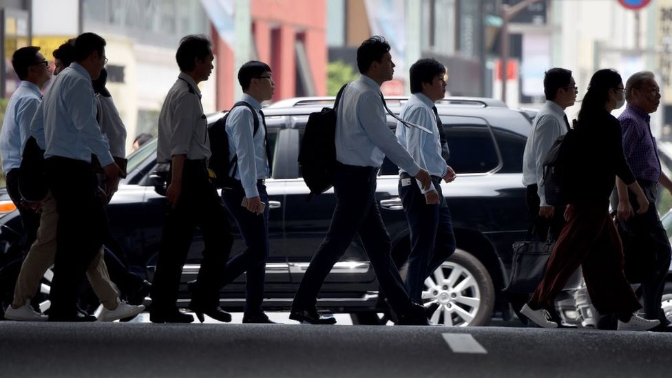 Expertos dicen que los altos niveles de automatización son una amenaza para los trabajos japoneses. Office workers and pedestrians cross a street in Tokyo