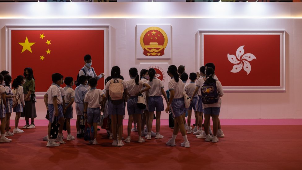 一群小學生在香港特區成立25週年展覽上觀看有關中國國旗與香港區旗的展板（2/9/2022）