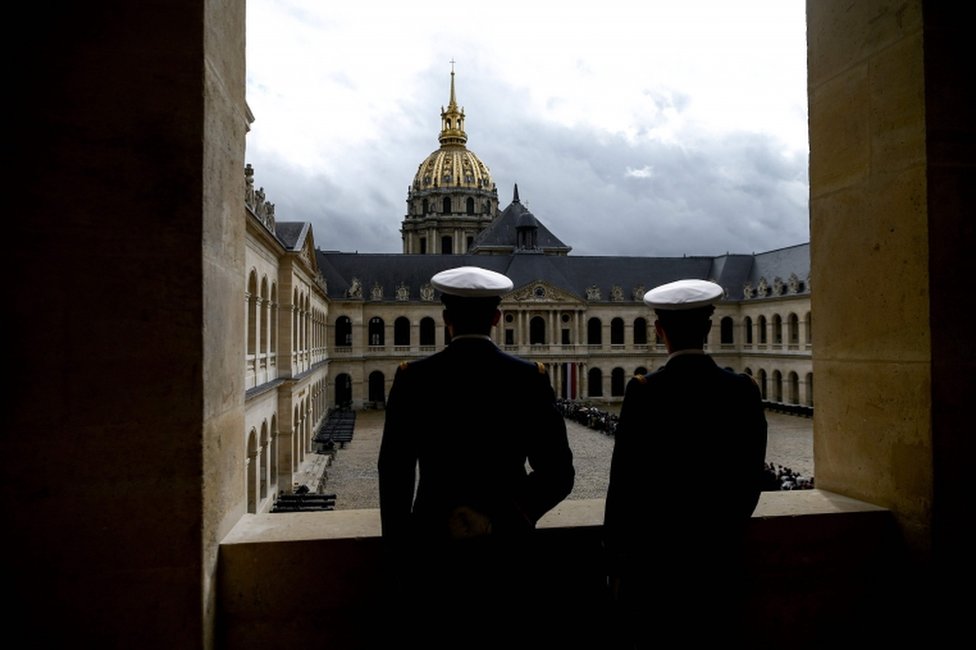 Servicemen look at people queuing to say a final farewell to former French President Jacques Chirac on 29 September 2019.