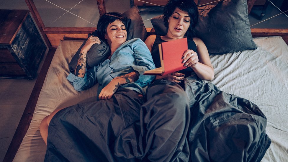 Dos mujeres en la cama leyendo un libro