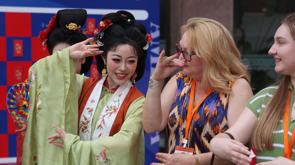 2024年6月12日，中國北京，一名身著中國傳統服裝的中國女性在中美青少年友誼主題音樂會前向美國友人展示中國傳統禮儀。