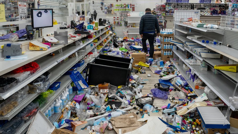 A business owner walks in his looted beauty supply store following protests over the police shooting death of Walter Wallace in Philadelphia