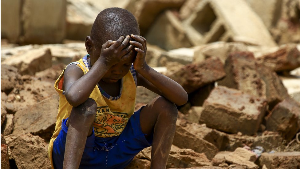 طفل سوداني يجلس مطرقا خارج منزل عائلته الذي دمره الفيضان