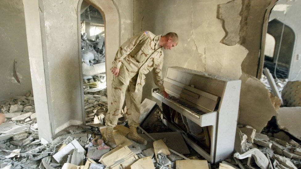Un soldado de EE.UU. revisa un piano en uno de los palacios de Saddam Hussein.