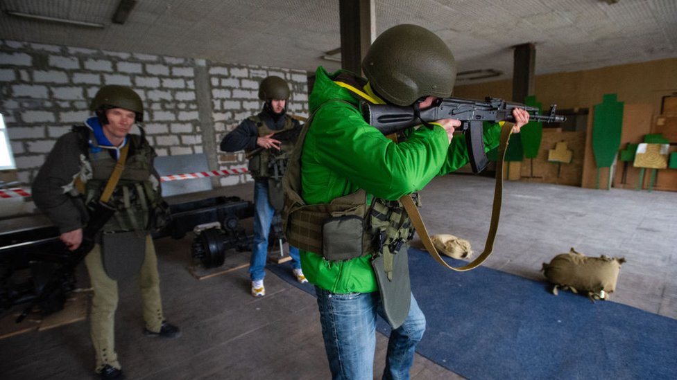 Personal militar en Ucrania le enseña a un civil a manejar armas.