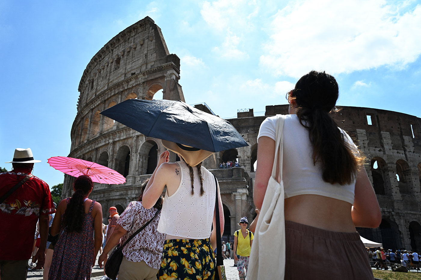 Tourists shelter from the sun with umbrellas near the Colosseum in Rome, on July 14, 2023