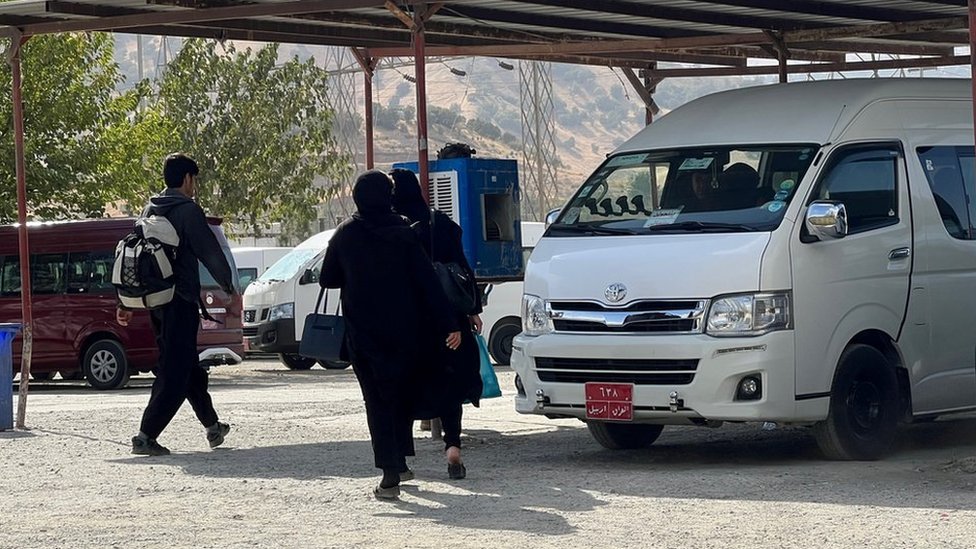 People walk at a bus station in Penjwen, an Iraqi town close to the crossing post on the border with Iran