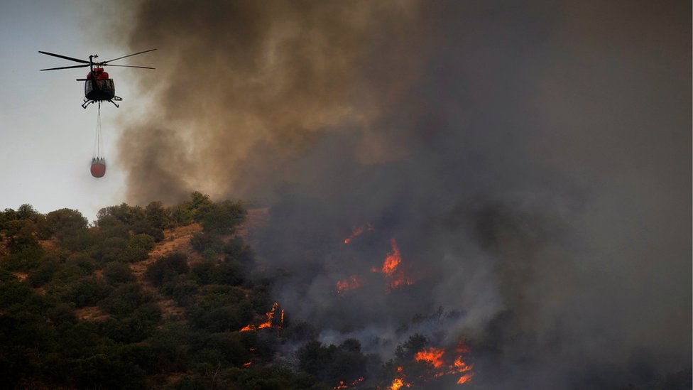 Вертолет пролетает над лесным пожаром недалеко от города Толедо