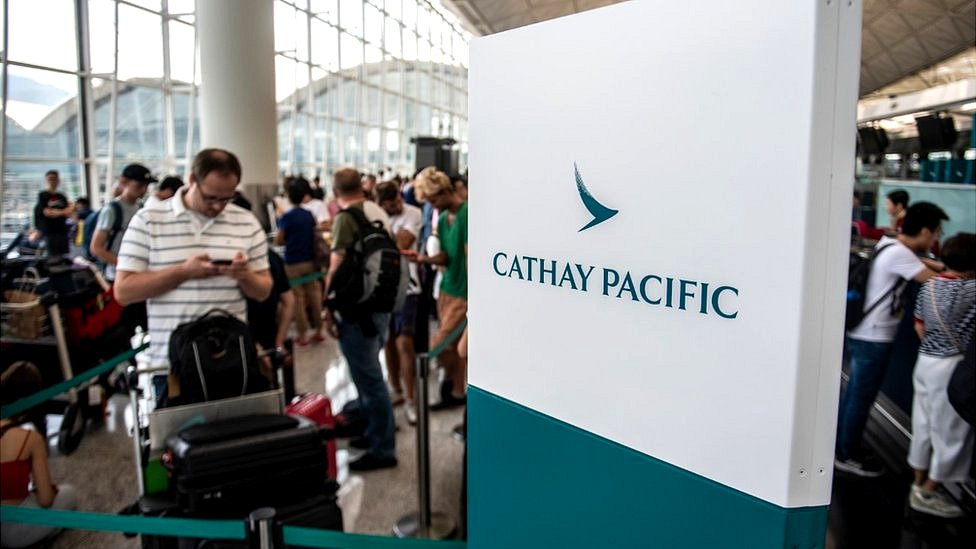 Логотип Cathay Pacific (R) рядом с Путешественником (L) в международном аэропорту Гонконга в Гонконге 13 августа