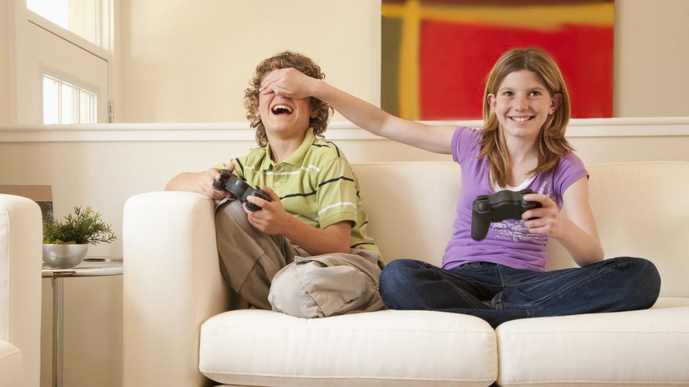 Brother and sister playing video games at home together