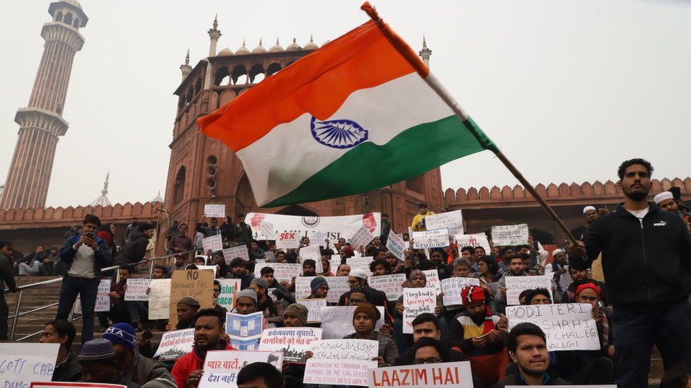 Студент машет индийским флагом во время митинга протеста против Закона о поправках к гражданству (CAA) на лестнице Джама Масджид в Старом Дели, Индия, 19 декабря 2019 года