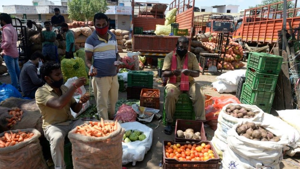 A farmer (C) negotiates prices with traders at a wholesale vegetable market in Hyderabad on August 31, 2020.
