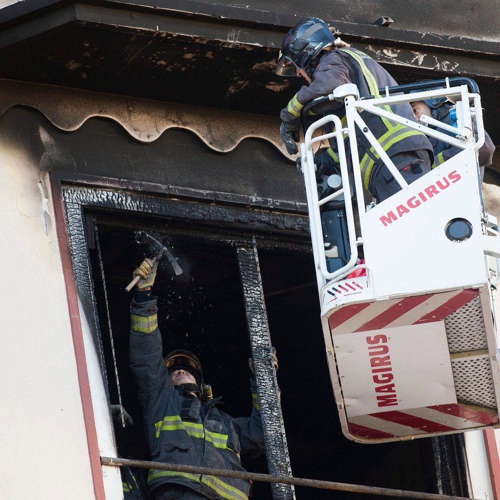 Пожарные осматривают обгоревшее окно в здании, где пожар унес жизнь 12-летней девочки в Сарагосе, Испания, 6 ноября 2016 г.