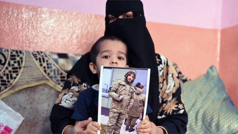 穆罕默德·阿斯凡的妻子和孩子拿著他的照片