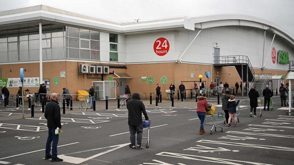 People queue for supermarket while social distancing