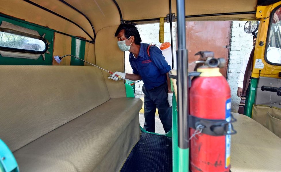 Персонал DTC по уборке химически дезинфицирует и дезинфицирует авто рикшу в качестве меры предосторожности в связи с опасениями, связанными с коронавирусом, в депо Васант Вихар 17 марта 2020 года в Нью-Дели, Индия.