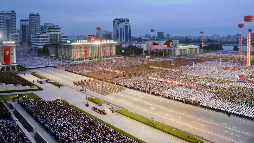 В Пхеньяне на забитой площади тысячи людей в одинаковых цветах аккуратными прямоугольными формами собрались перед зданиями, украшенными политическими знаменами