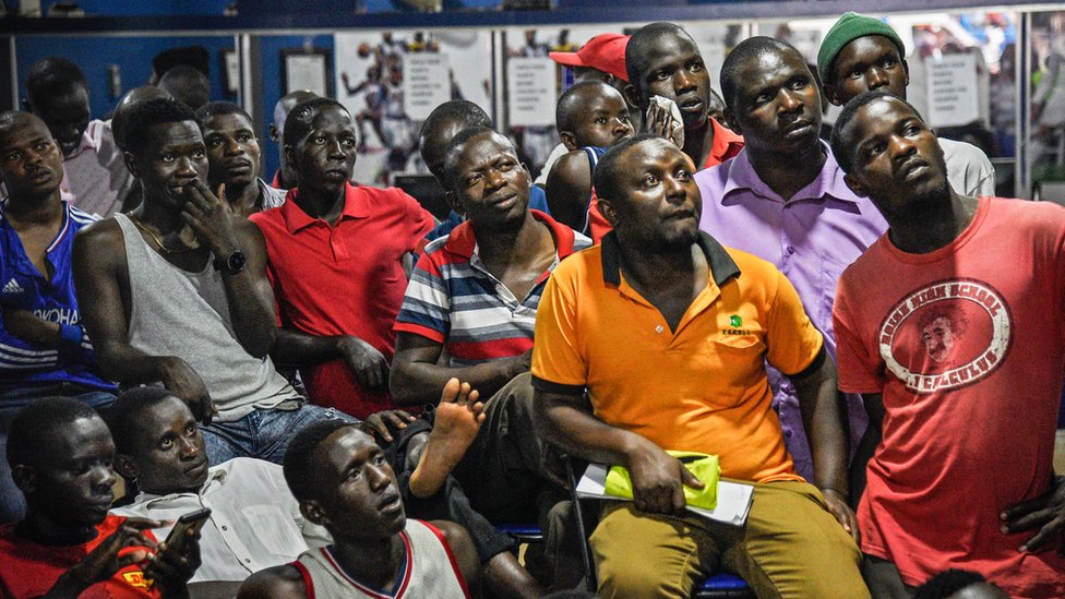 Мужчины смотрят телевизор в букмекерской конторе Уганды