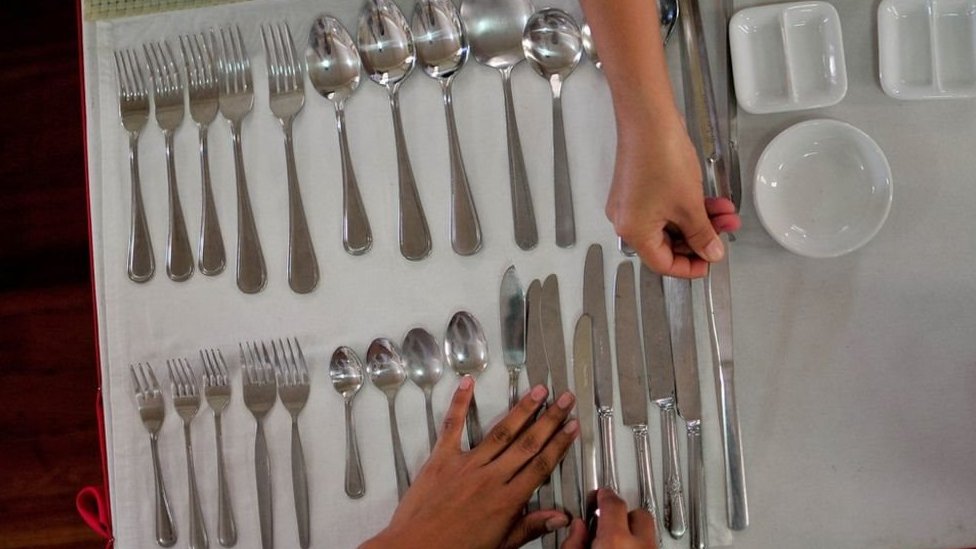 Los filipinos siguen siendo muy poco visibles en la industria de servicios de muchos países. Mujer ordena los cubiertos en una mesa