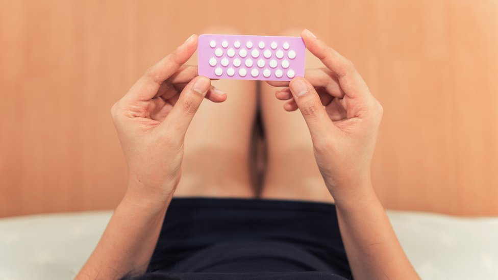 Mujer agarrando tabla de pastillas anticonceptivas.