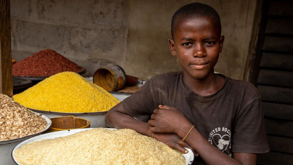 Un niño posa cerca de un abastecimiento de arroz en un mercado cerca de Lagos.