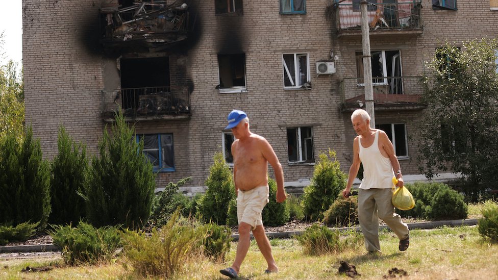 Ukrainian men walk in front of damaged houses following recent Russian shelling, as Russia's attack in Ukraine continues, in the city of Slovyansk, in Donetsk region, Ukraine August 28,2022. REUTERS/Ammar Awad