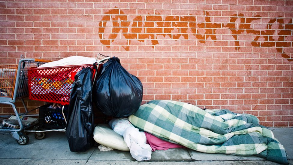 Una persona duerme en la calle entre unas mantas