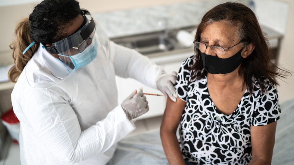 Mulher é vacinada por profissional da saúde