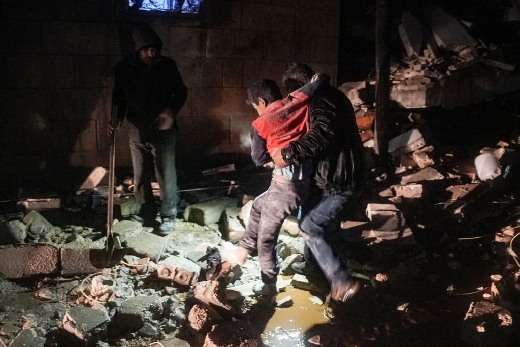 رجل يحمل طفلا مصابا من جراء الزلزال في بلدة جندريس بريف مدينة عفرين شمال غربي سوريا في الجزء الخاضع لسيطرة الثوار من محافظة حلب، مطلع 6 فبراير /شباط 2023
