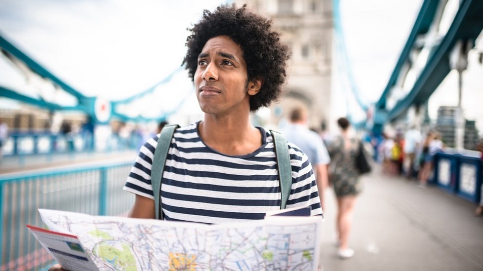 Un hombre joven sosteniendo un mapa en Tower Bridge, Londres.