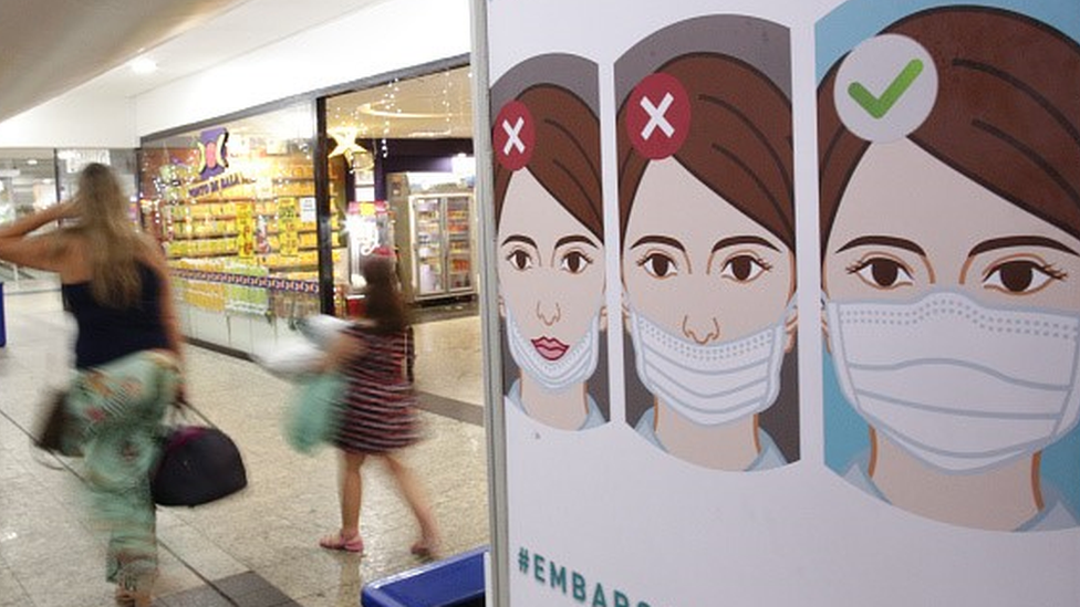 Panel informativo sobre el uso correcto de mascarillas en un aeropuerto.