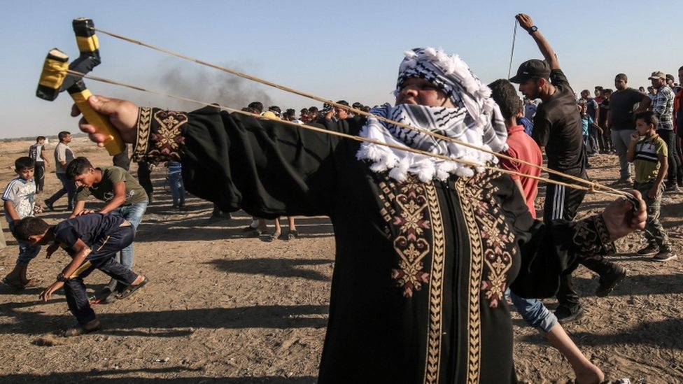 Gazze Şeridi'ndeki Filistinli bir kadın İsrailli güvenlik güçlerine taş atıyor