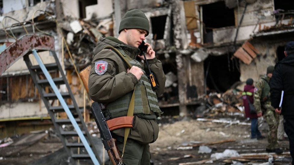 Soldado frente a edificio residencial alcanzado por fuego de morteros en Kiev.
