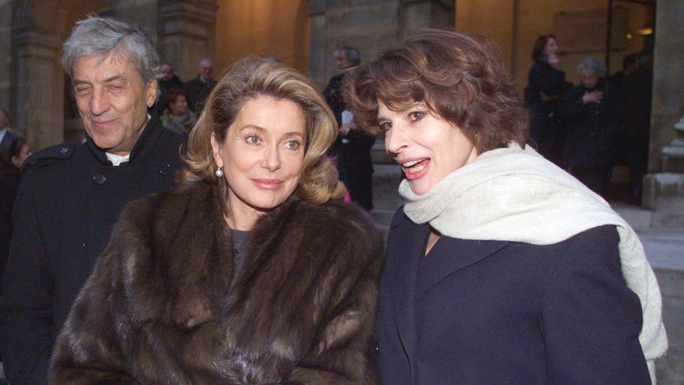 Las actrices francesas Catherine Deneuve y Fanny Ardant y el diseñador italiano Nino Cerruti salen de la Academia de las Bellas Artes de París el 15 de diciembre de 1999.