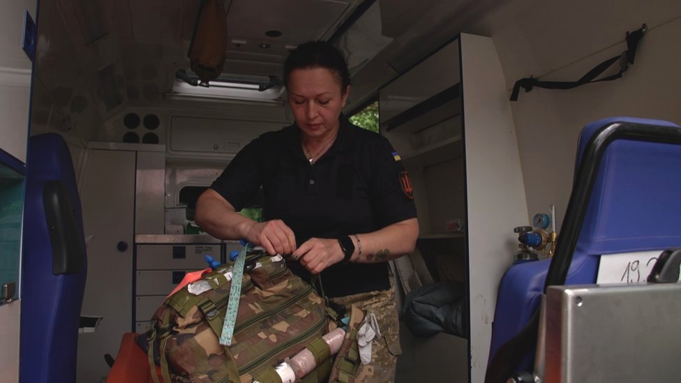 Tina packing a military bag inside an ambulance