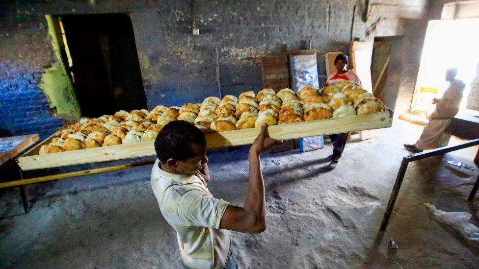 عامل يحمل لوحا عليه أرغفة من الخبر في أحد المخابز في الخرطوم