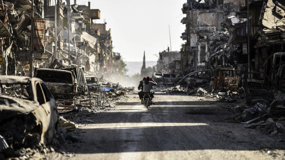 Sirijski mladić snima telefonom uništena vozila i zgrade u gradu Raka 20. oktobar 2017.