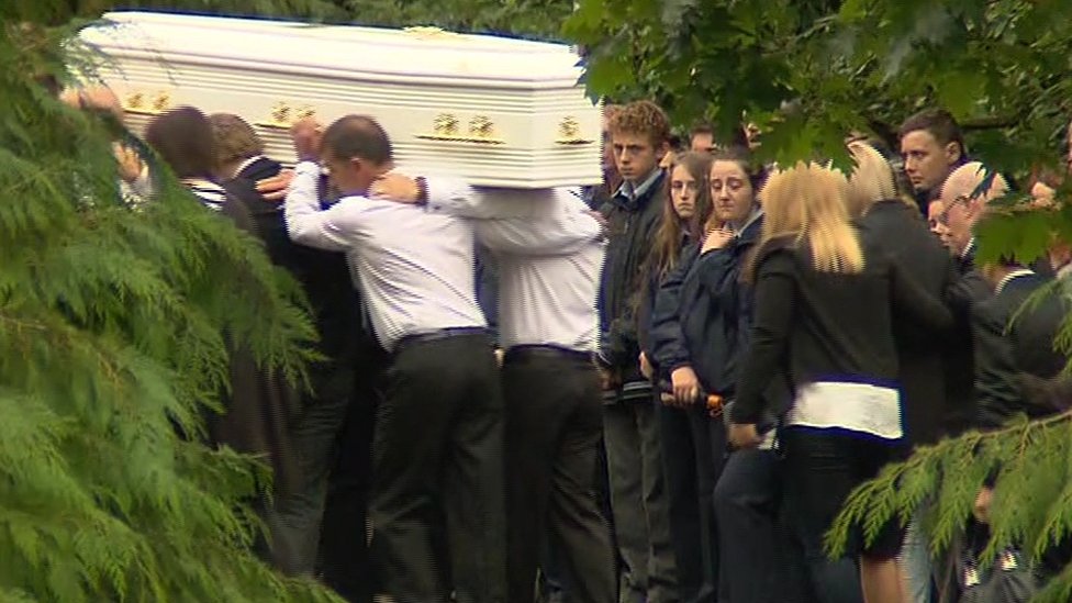 Скорбящие наблюдают, как проходит гроб во время похорон семьи Хаве