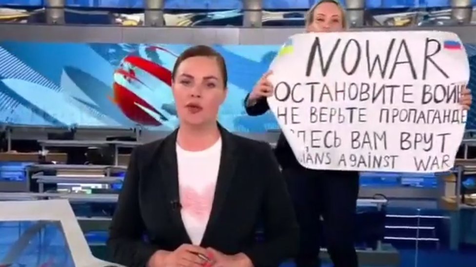 Manifestante en un estudio de televisión de Rusia con una pancarta en contra de la guerra.