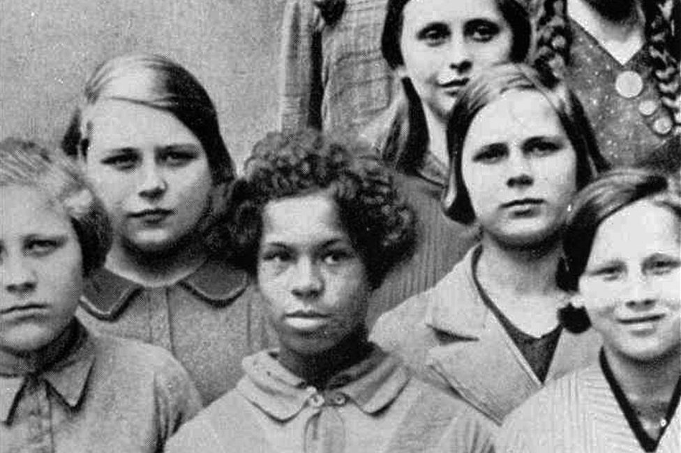 Esta foto fue usada en conferencias sobre genética de la Academia Nacional para la Raza y la Salud, en Dresden, Alemania, 1936. Título original: "niña mulata de una mujer alemana y un negro de las tropas de al Renania francesa, entre sus compañeros de clase alemanes".